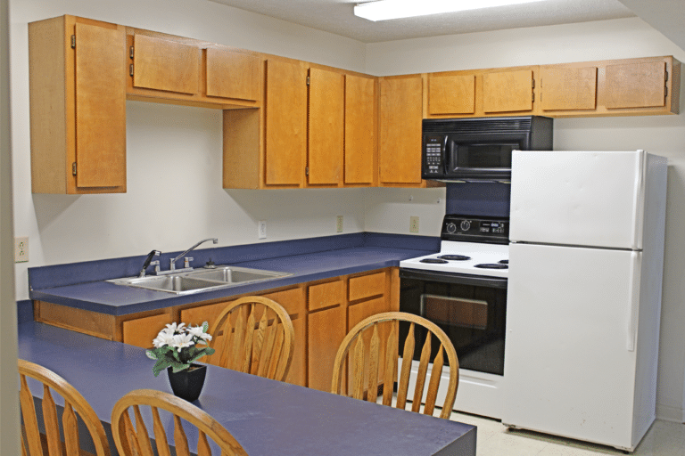 Young Hall公寓内的厨房. 有冰箱、炉子、微波炉、水槽和桌子.